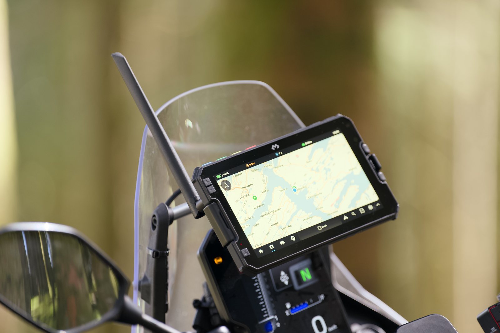 A DMD tablet mounted on a motorcycle behind the windscreen, showing a coastal map while riding
